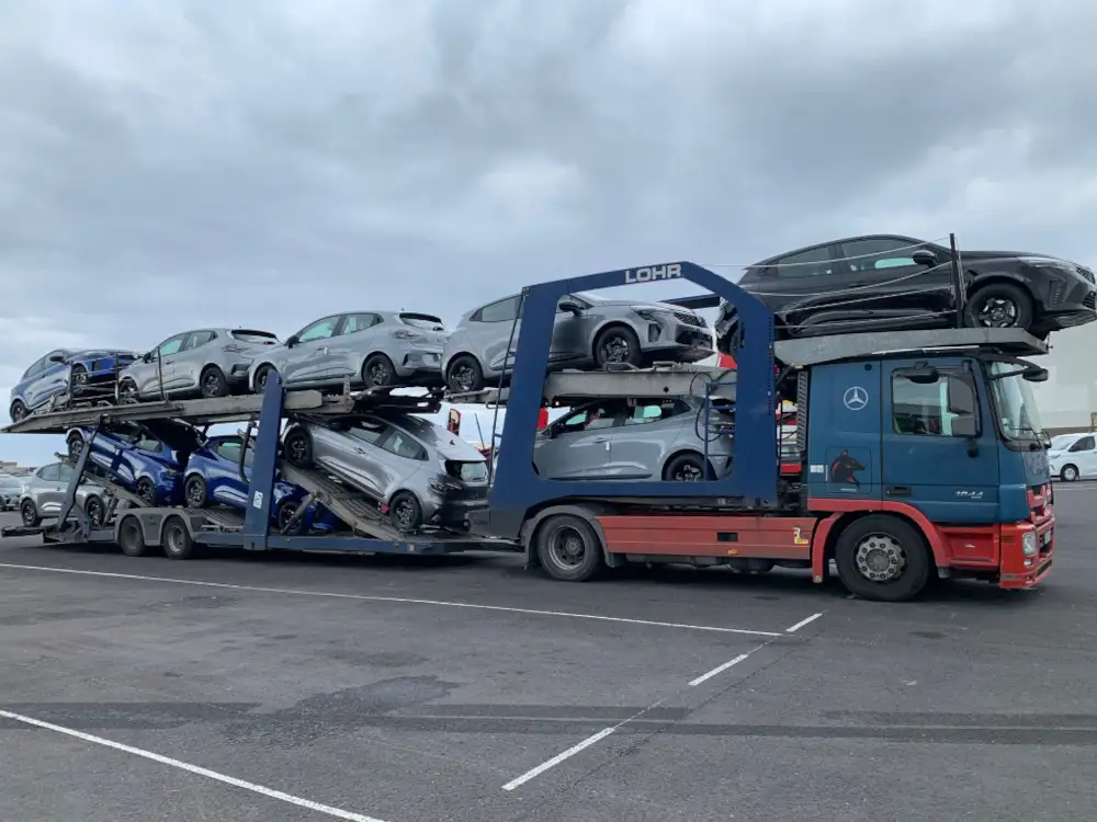 Camion porte-voitures chargé de véhicules sur un parking